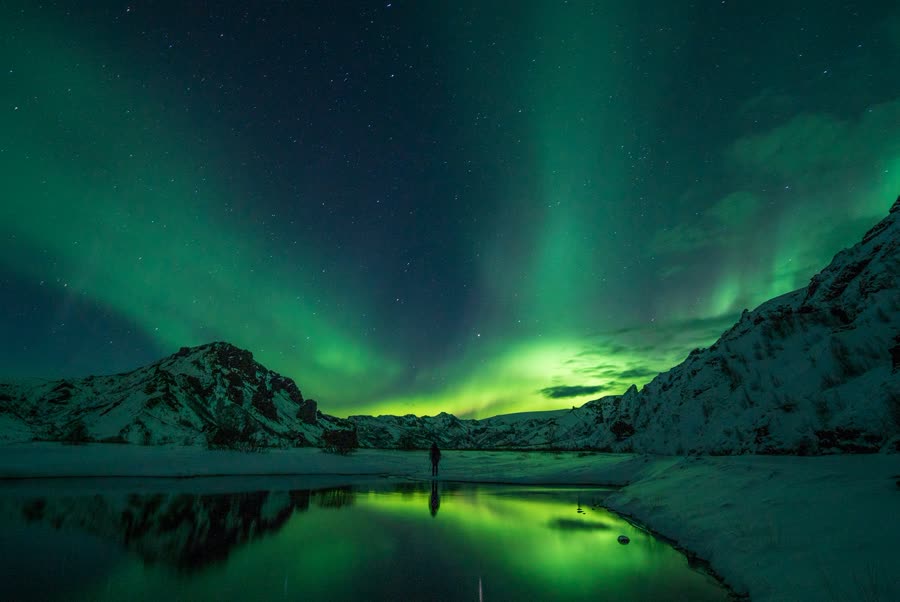 The northern lights glowing over a snow-covered peak in Iceland