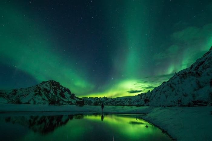 The northern lights glowing over a snow-covered peak in Iceland